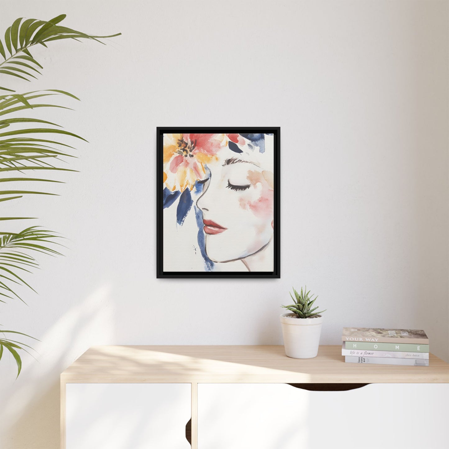 Multi-Color Framed Matte Canvas Art - Floral Face Portrait hanging on a white wall above a modern desk with a plant and books.
