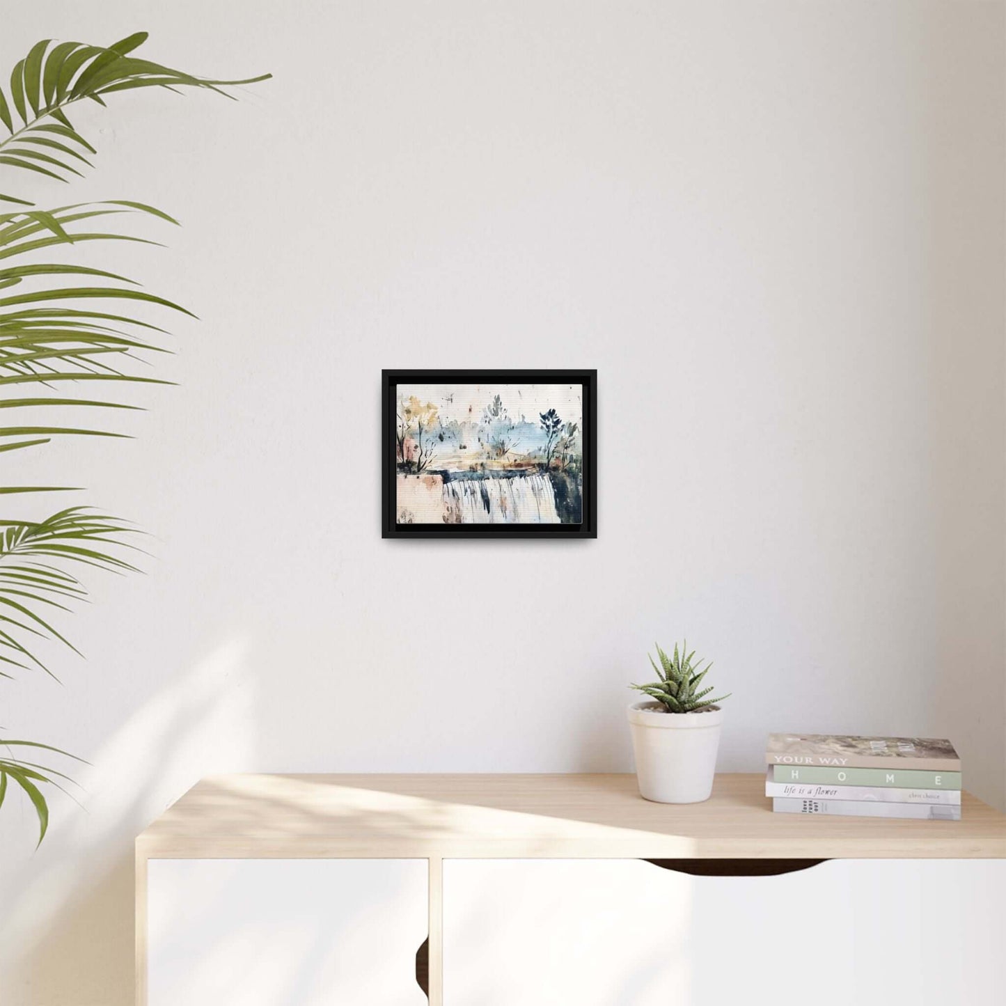 Framed watercolor landscape wall art on display, serene decor with potted plant and books on a modern shelf.