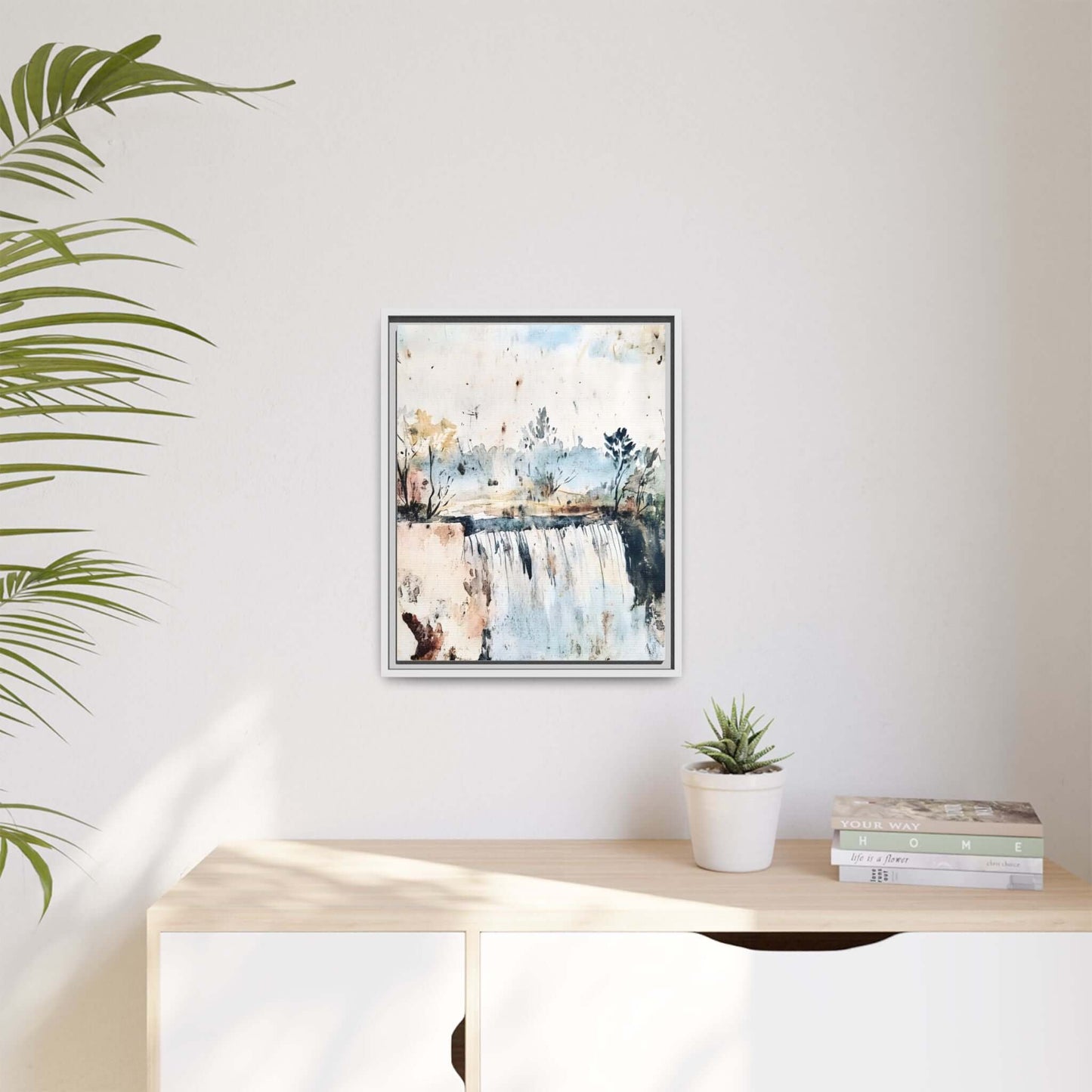 Framed watercolor wall art featuring serene landscape decor, displayed on a white wall above a wooden shelf with plant and books.