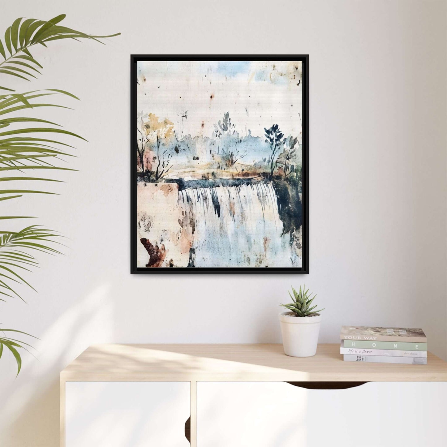 Framed watercolor wall art depicting a serene landscape on a modern wall, accompanied by a potted plant and books on a shelf.