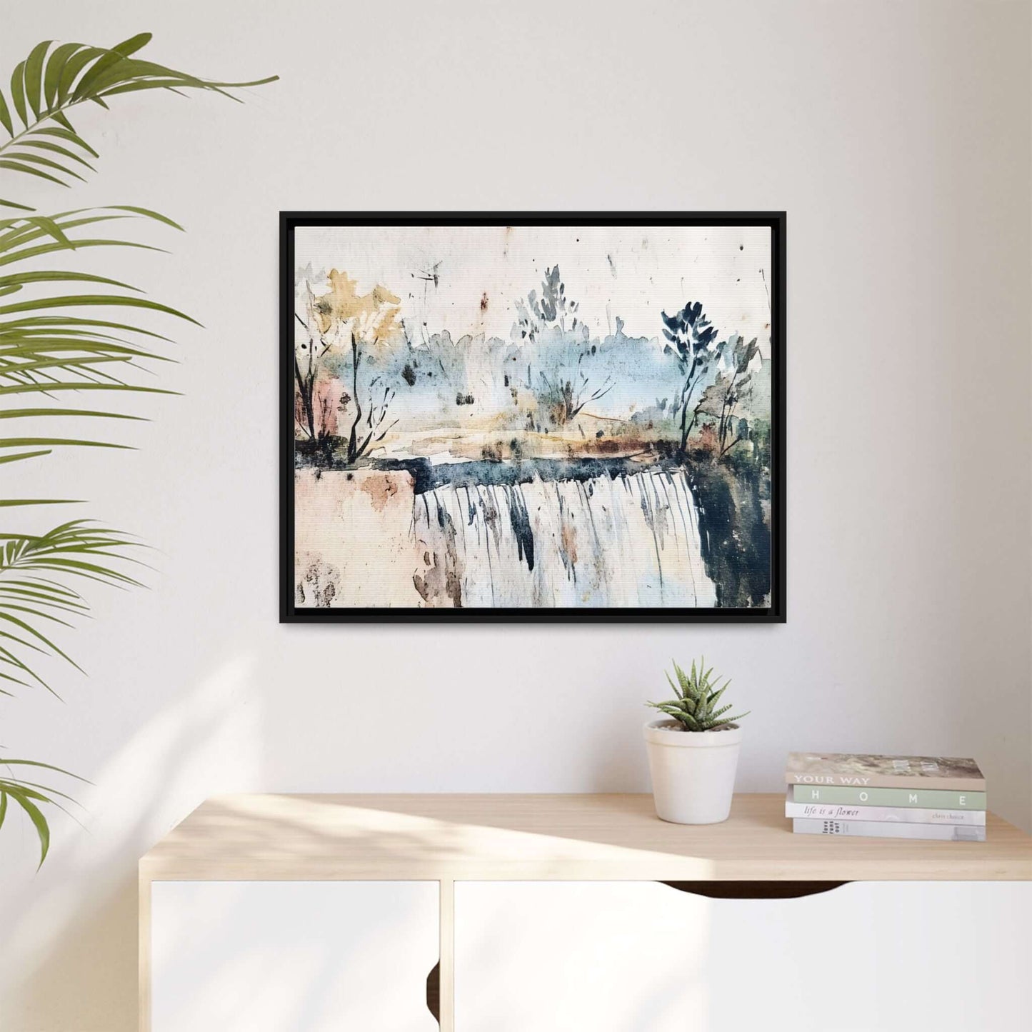 Framed watercolor wall art depicting a serene landscape, featuring a waterfall and trees, mounted above a modern shelf with decor.