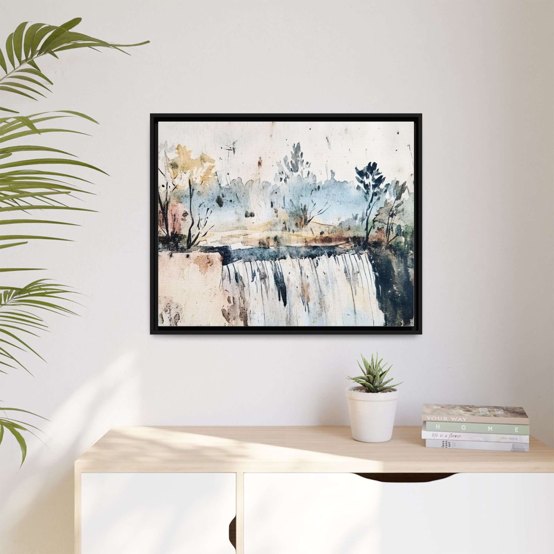 Framed watercolor wall art depicting a serene landscape, featuring a waterfall and trees, mounted above a modern shelf with decor.