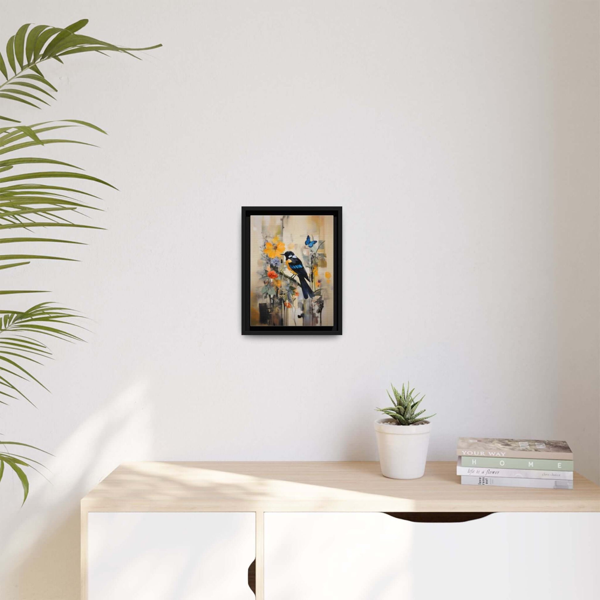 Framed colorful bird and butterfly canvas art, vibrant home decor, displayed on a light-colored wall above a wooden table with plants.