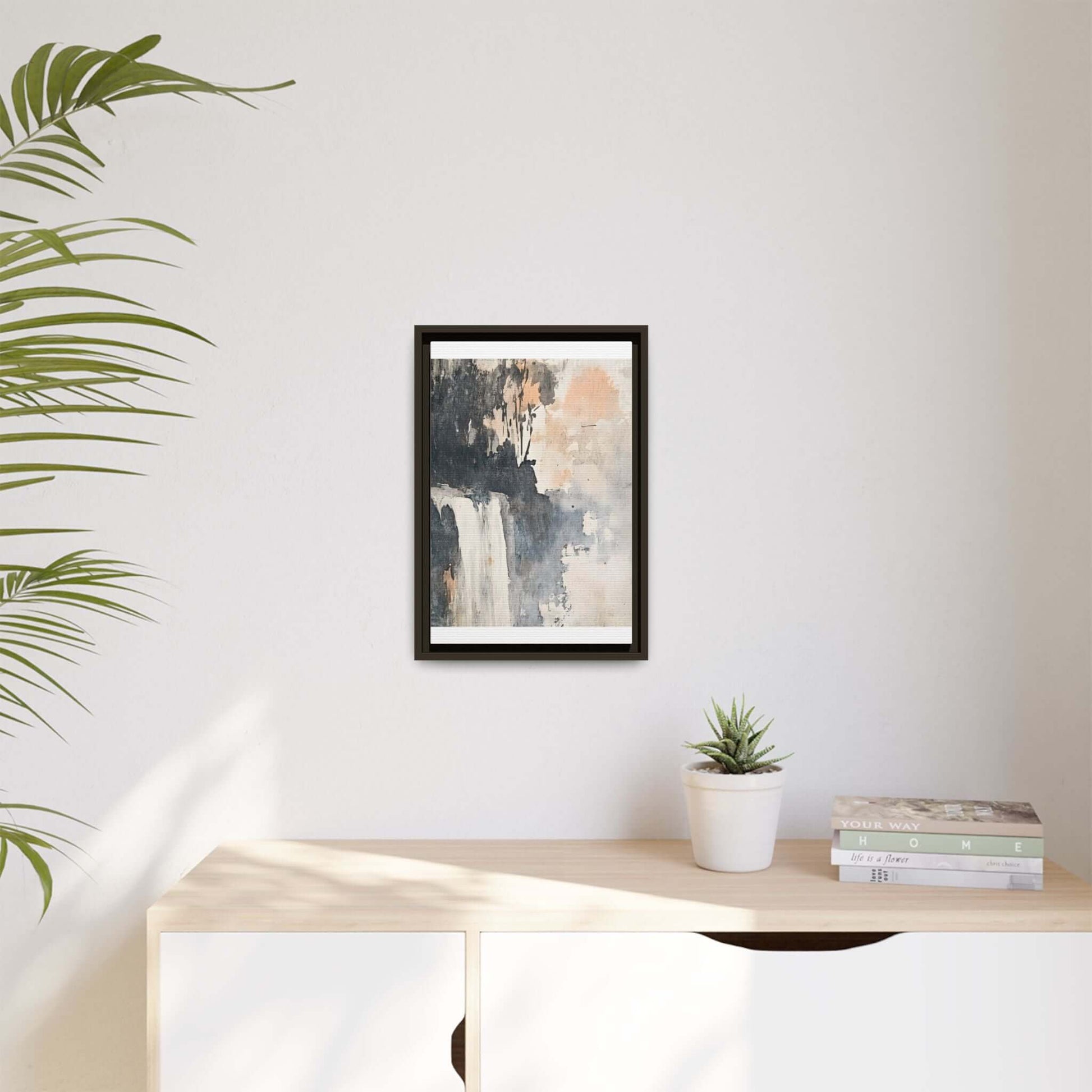 Framed waterfall art print on matte canvas displayed on light wood shelf with potted plant and books, minimalist home decor.
