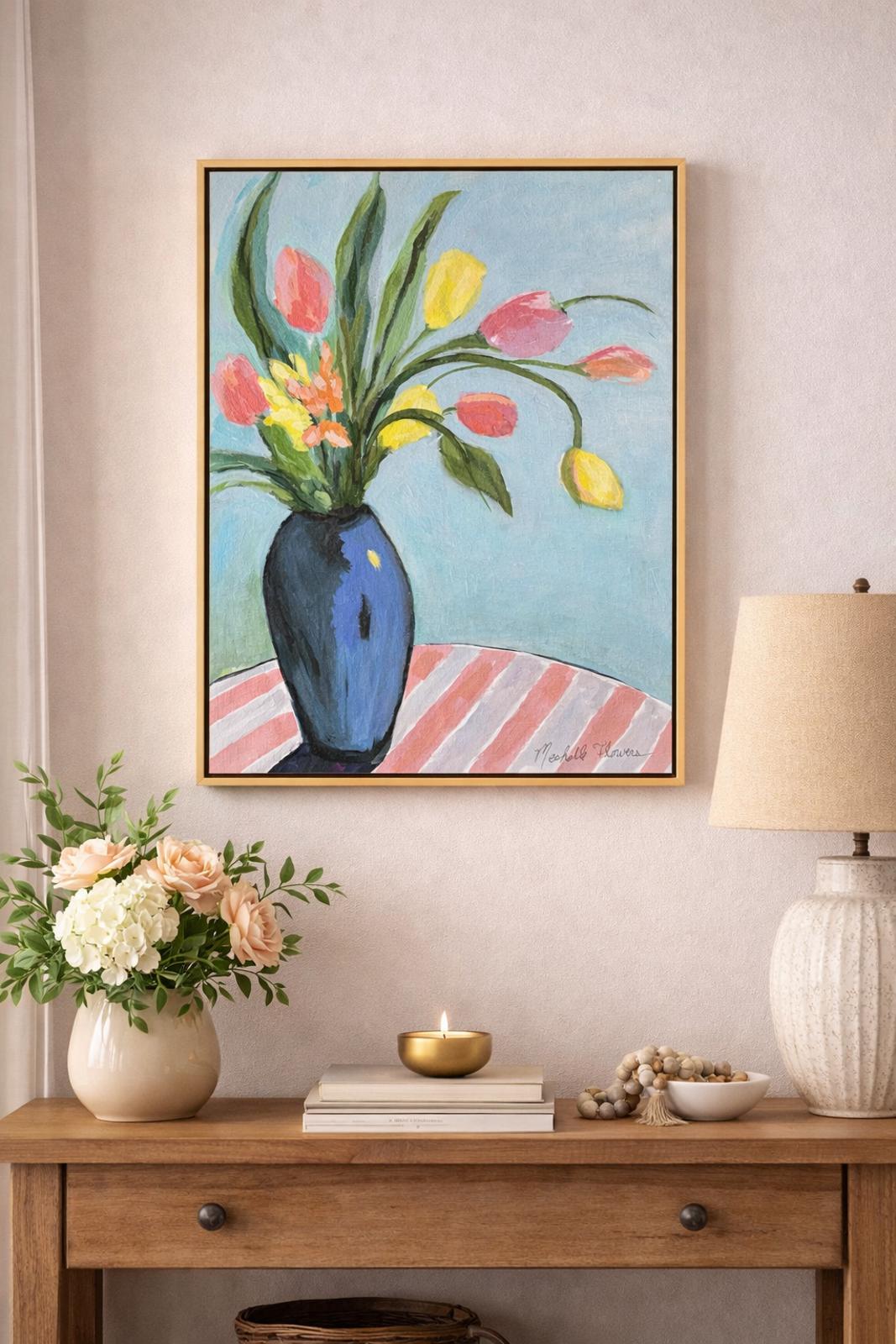 Framed artwork of flowers on a wall above a wooden console table with decorative items.