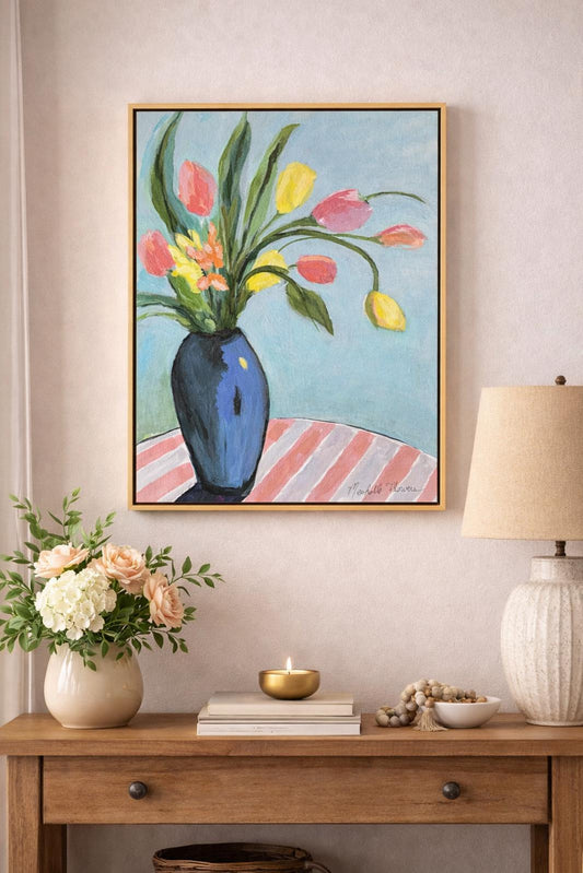 Framed artwork of flowers on a wall above a wooden console table with decorative items.