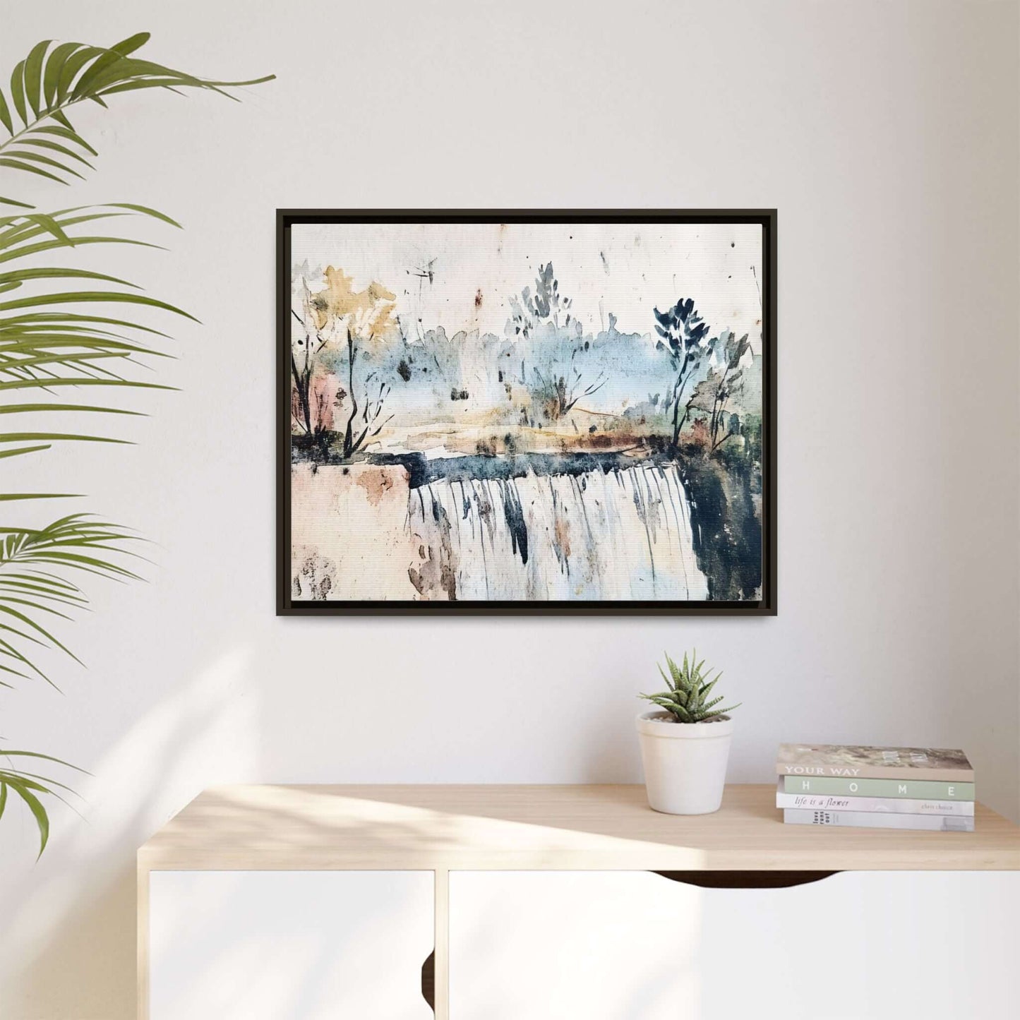 Framed watercolor wall art depicting a serene landscape with a waterfall, displayed in a minimalist room setting.
