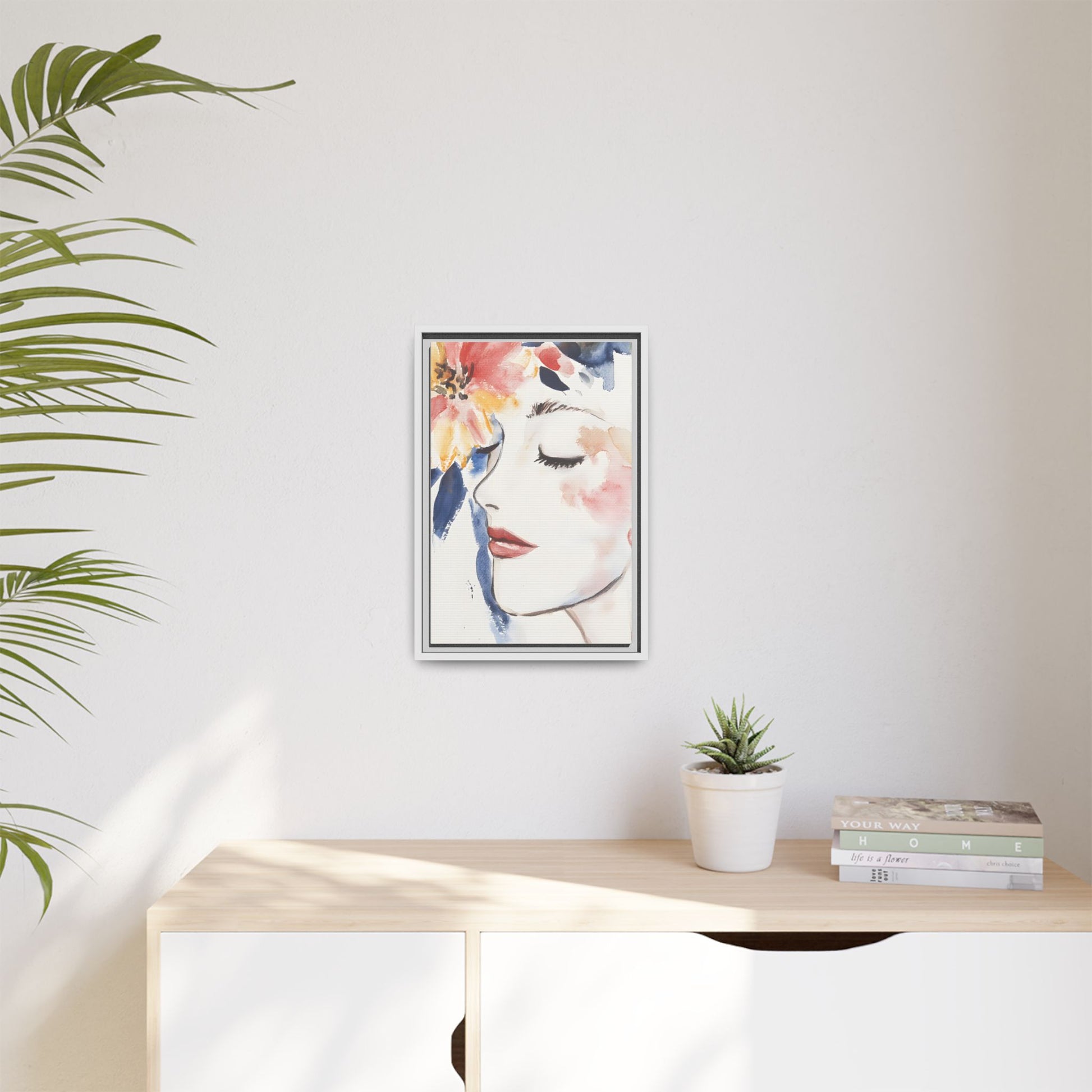 Multi-Color Framed Matte Canvas Art - Floral Face Portrait hanging in modern room with plant and books.