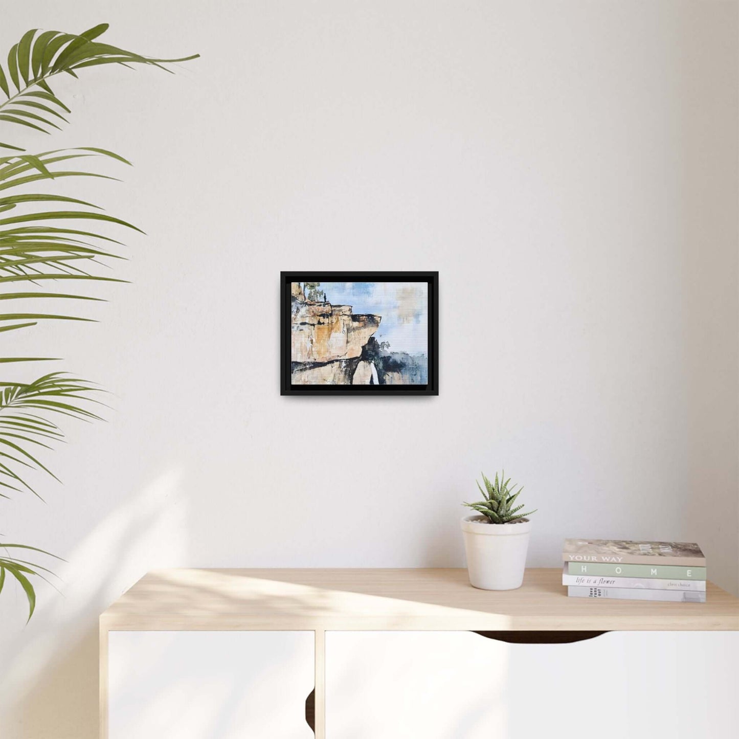 Impressionistic scenic landscape waterfall framed canvas wall art on a modern shelf with potted plant and books.