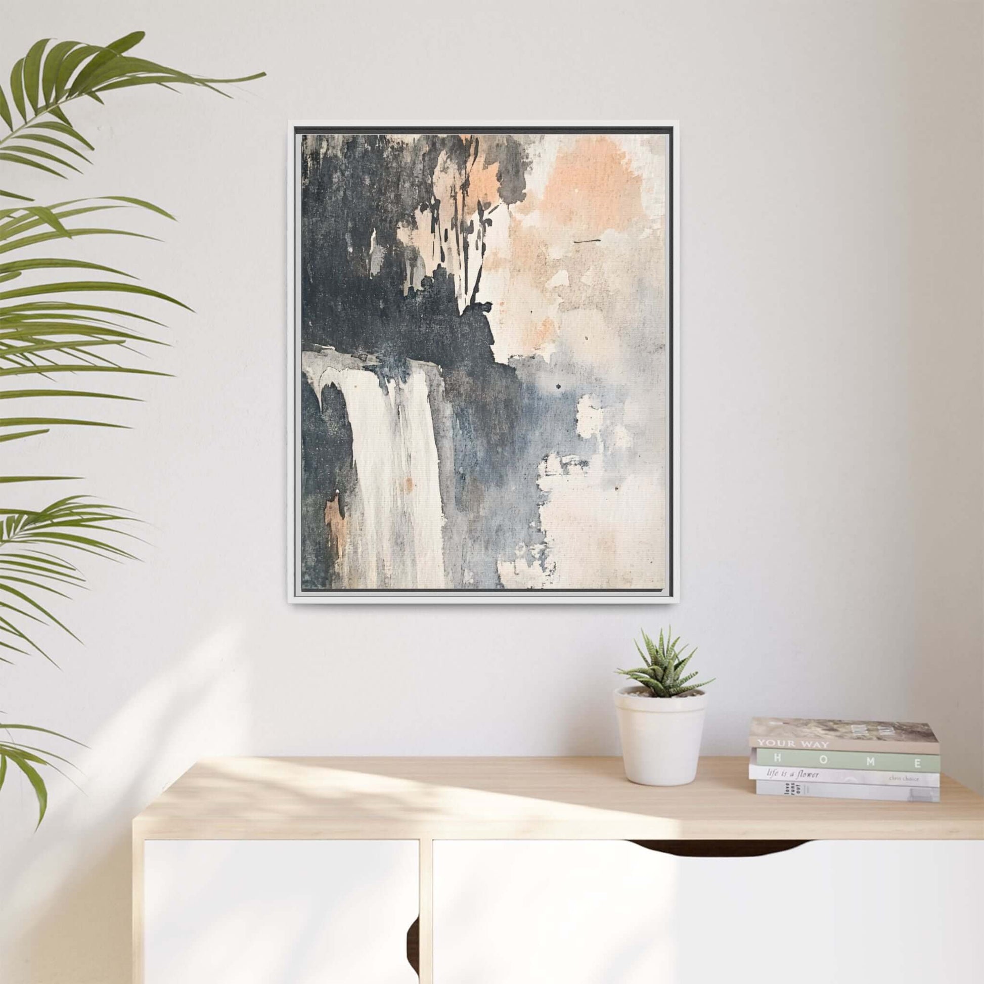 Framed abstract waterfall art print on matte canvas in modern home decor setting with plant and books.