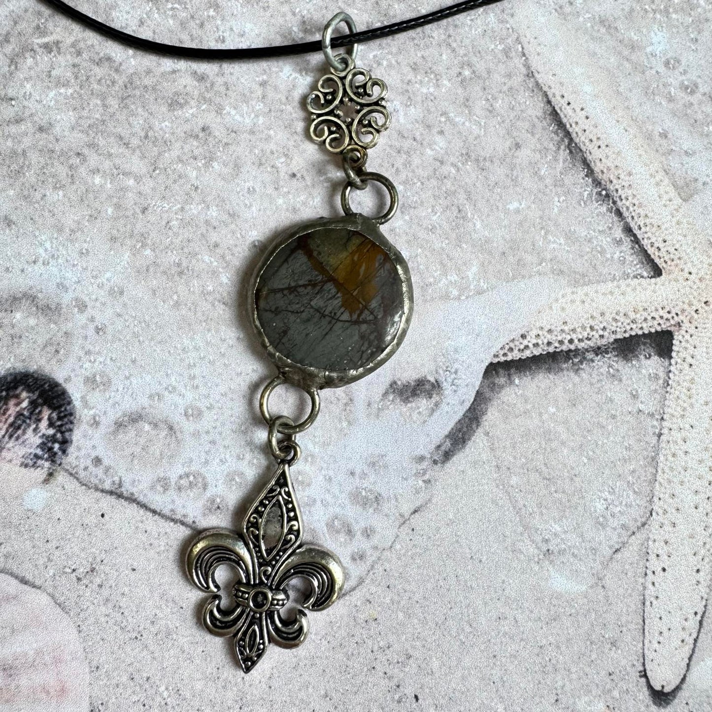 Handmade Natural Stone with Silver Tone Fleur-de-Lis Pendant on beach-themed background