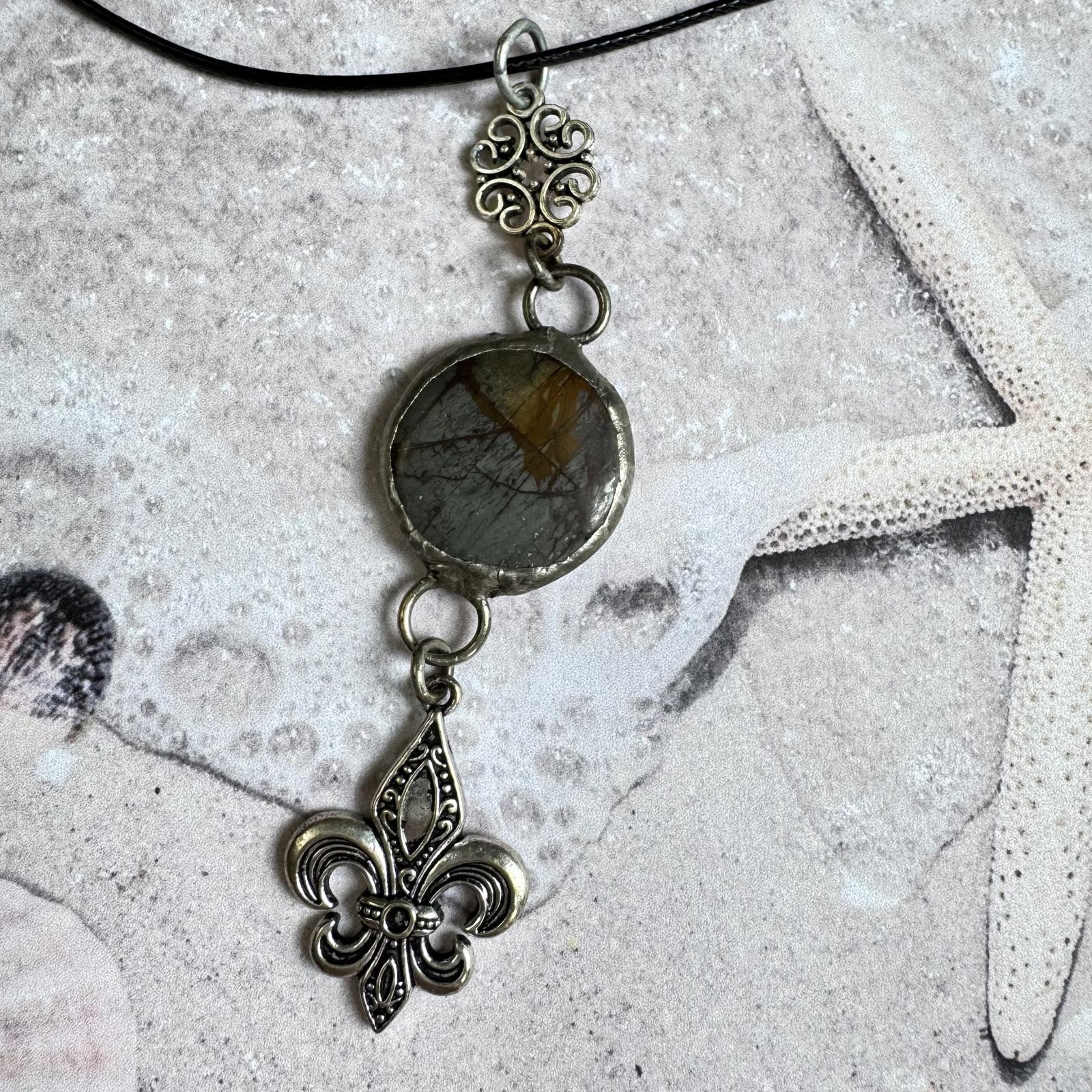 Handmade Natural Stone with Silver Tone Fleur-de-Lis Pendant on beach-themed background