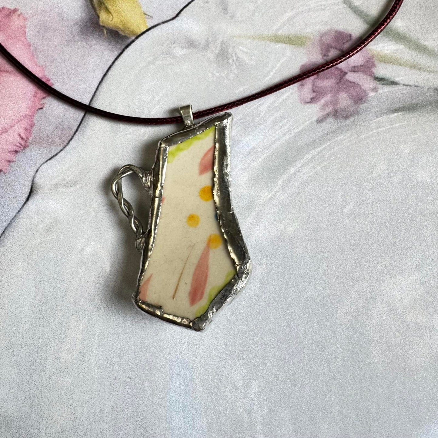 Broken China Teapot Shape Handmade Floral Pendant with pastel floral design on cream background, silver-tone framing, elegant accessory.