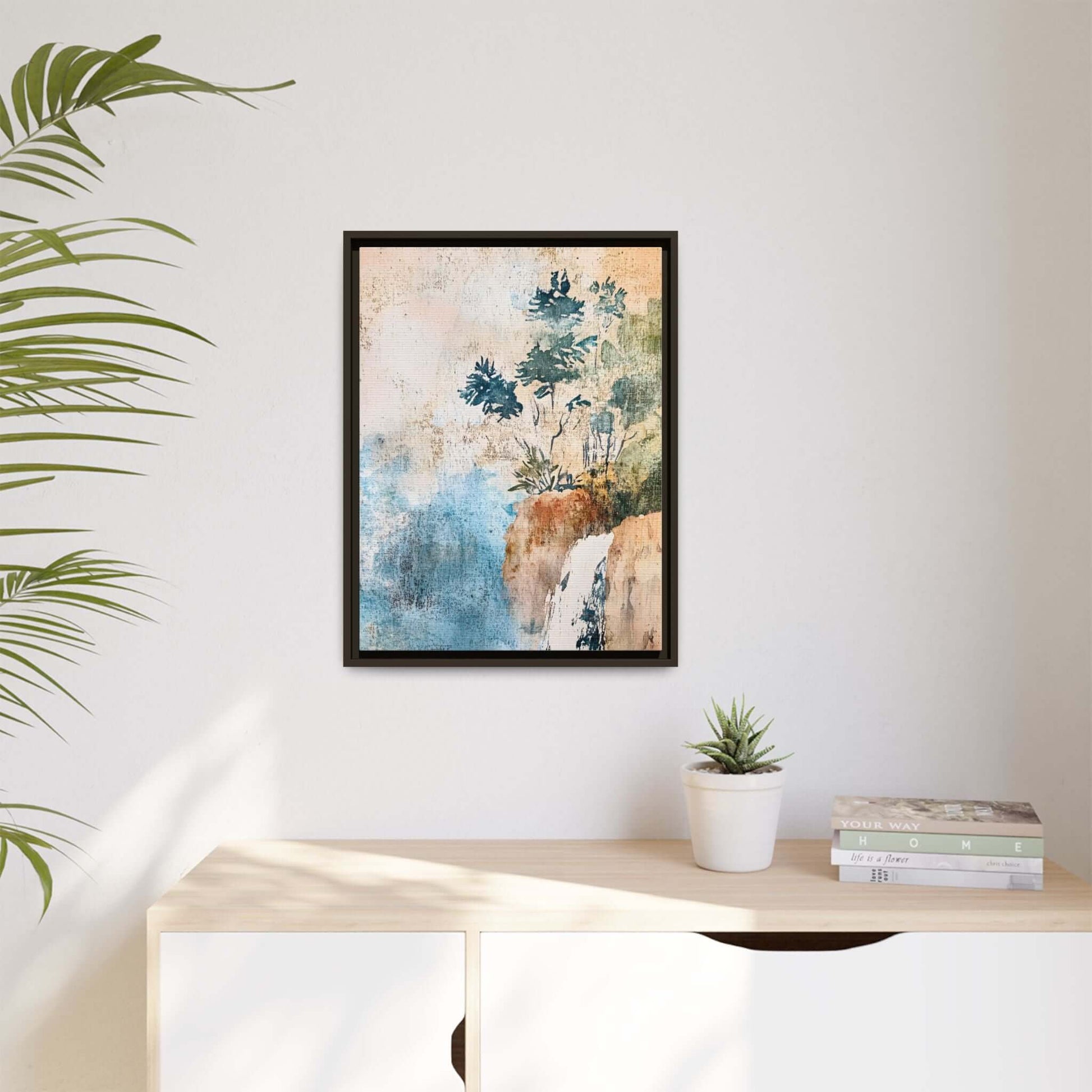 Framed watercolor canvas print of a serene misty forest landscape, hanging in a modern interior room with plants and books.