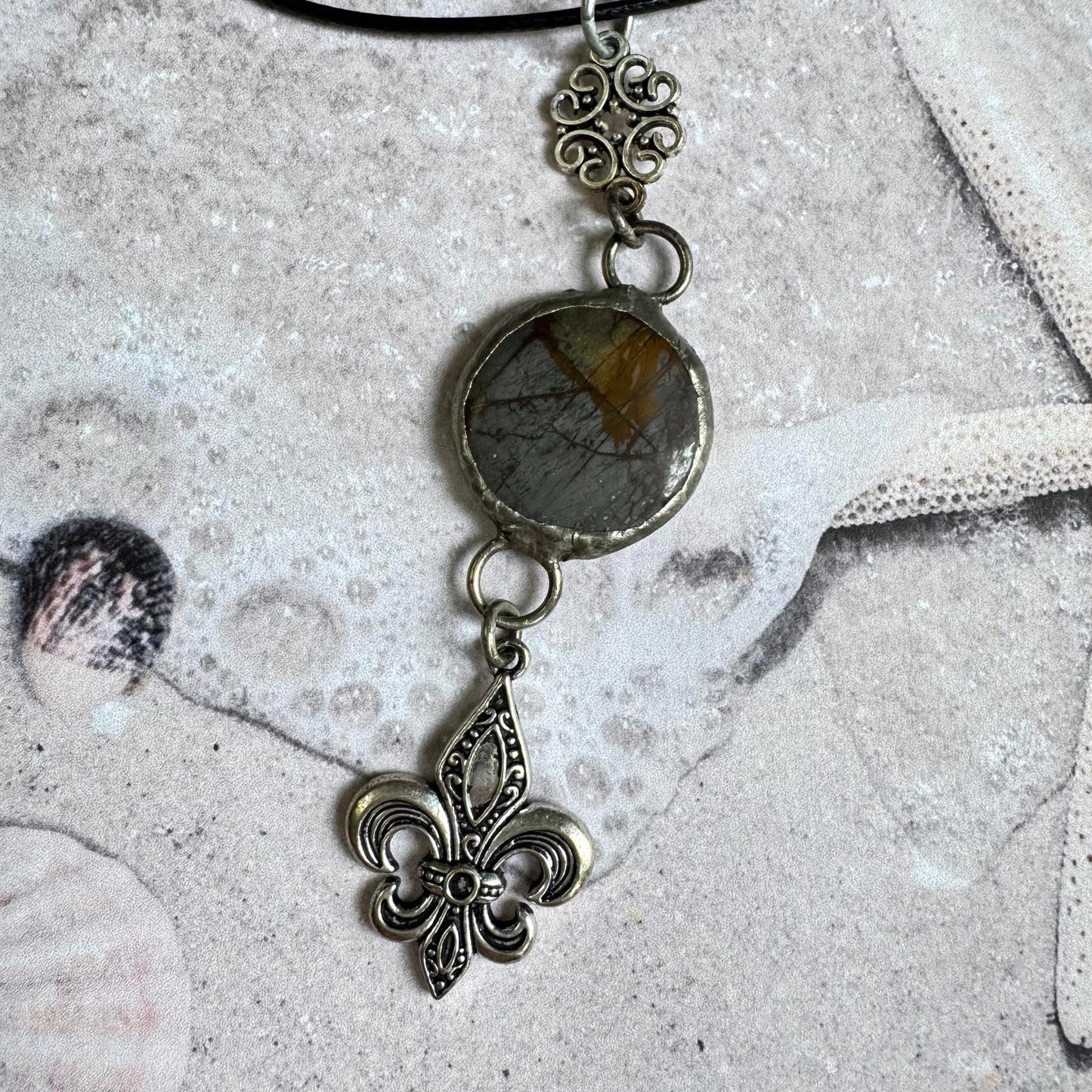 Handmade Natural Stone with Silver Tone Fleur-de-Lis Pendant featuring gray and amber hues on a durable black cord.
