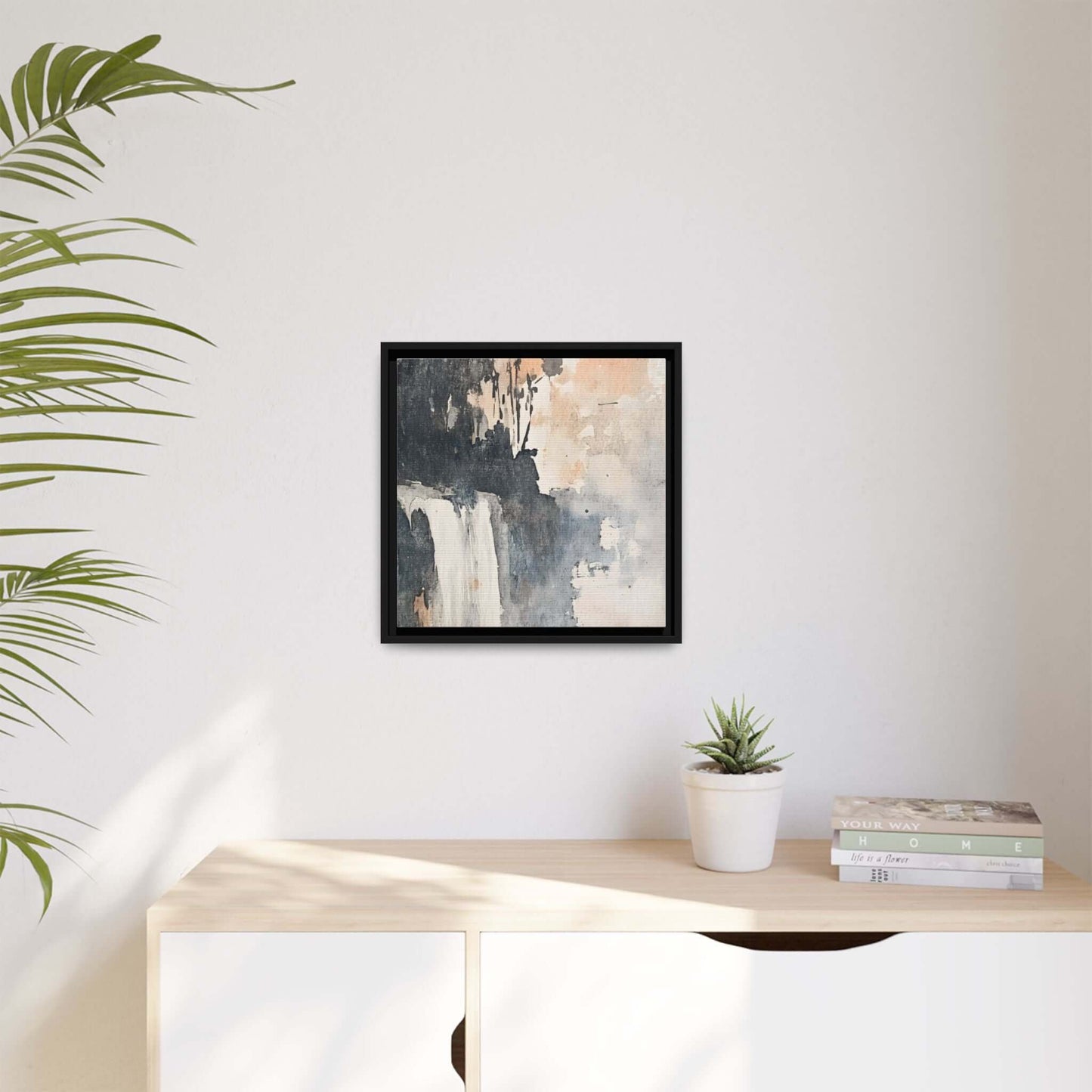 Framed waterfall art print in matte canvas, 16" x 16", vertical orientation on white wall; elegant home decor with plant and books.