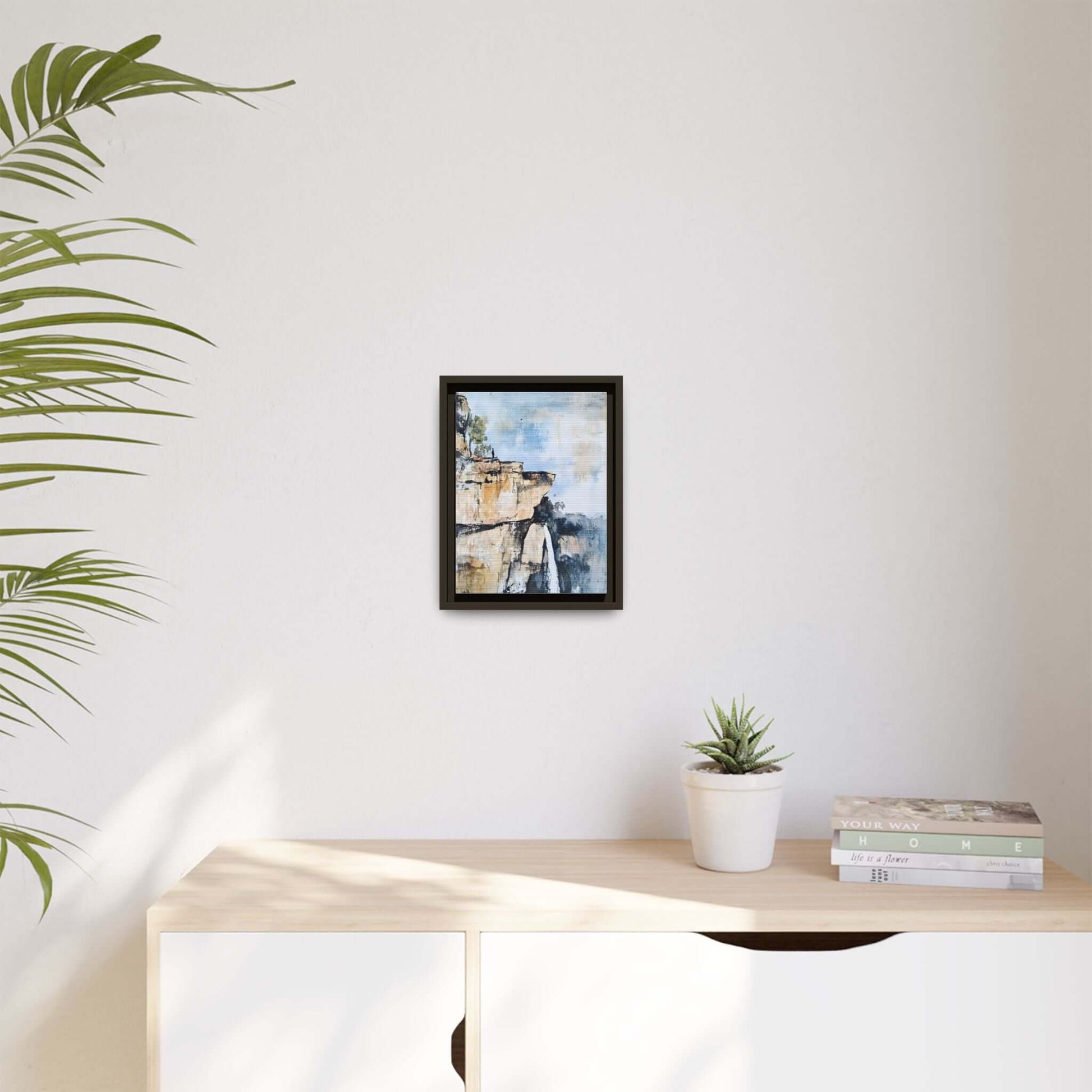 Impressionistic landscape waterfall art framed on wall, enhancing room decor with serene scenery, books, and plant nearby.