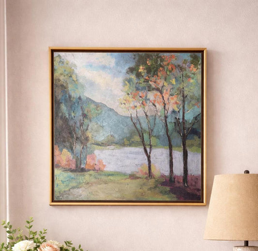 Framed landscape painting of trees by a lake on a wall.